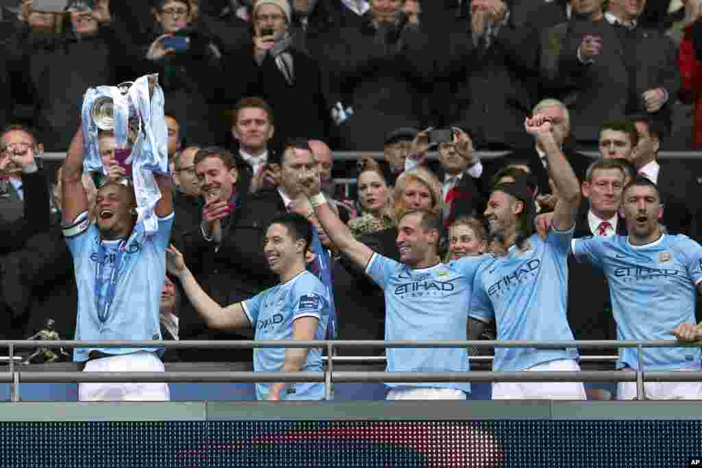 Vincent Kompanty na Manchester City rike da kofin yayin da sauran 'yan wasa ke nuna murnarsu.