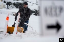 A man clears a sidewalk as a winter storm arrives on Jan. 12, 2024, in Milwaukee, Wisconsin.