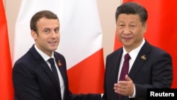 Le président français Emmanuel Macron échange une poignée de mains avec son homologue chinois Xi Jinping.