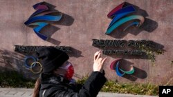 A woman takes photos near the logos for the Beijing Winter Olympics and Paralympics in Beijing, China, Nov. 9, 2021. China on Dec. 7 accused the United States of violating the Olympic spirit by announcing an American diplomatic boycott of February's Beijing Winter Games.