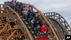 Para pengunjung taman hiburan mengendarai roller coaster (foto: ilustrasi).