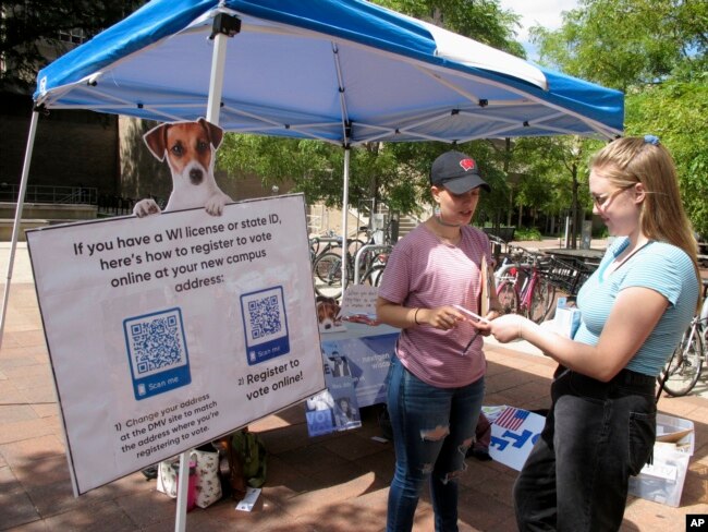 NextGen America campus organizer Simone Williams, left, talks with Grace Austin, a junior at the University of Wisconsin, about how to register to vote in Madison, Wis.