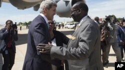 South Sudanese Foreign Minister Barnaba Marial Benjamin, right, welcomes US Secretary of State John Kerry upon his arrival at Juba International Airport, South Sudan, Friday May 2, 2014. Kerry, landing in the capital Juba on Friday, has threatened U.S.sanctions against South Sudanese leaders. 