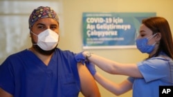 A health worker administers the first dose of a COVID-19 vaccine currently on phase III clinical trials to Cem Gun an Emergency Medicine Physician at the Acibadem Hospital in Istanbul, Friday, Oct. 9, 2020. The vaccine was developed in China by Sinovac Biotech.