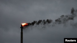 Awan gelap Badai Harvey terlihat di belakang sementara asap membumbung dari cerobong pembakaran sebuah kilang minyak di Corpus Christi, Texas, 27 Agustus, 2017.
