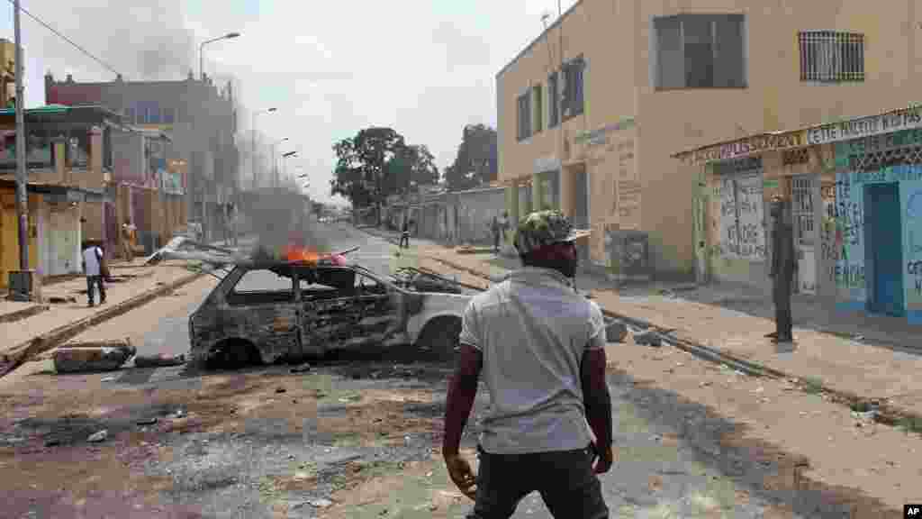 Un manifestant se trouve en face d&#39;une voiture calcinée que lui et les autres ont utilisés pour barricader les routes lors des manifestations, le 20 janvier 2015.