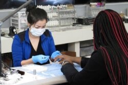 Xuan Le wears a mask as she works on the nails of Deriana Hayward at Envy Nail Bar on April 24, 2020, in Savannah, Ga.