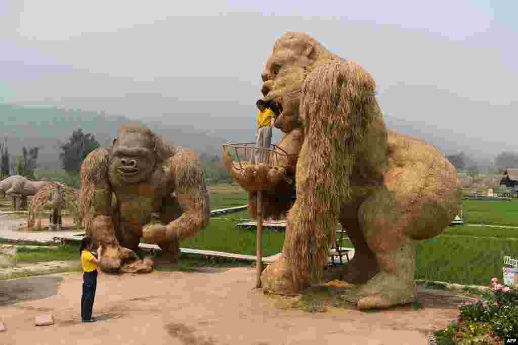 Seorang siswa memotret patung King Kong yang terbuat dari sedotan di provinsi Chiang Mai, Thailand utara.&nbsp;