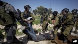 Israeli security forces detain a Palestinian protester during a demonstration marking the 10th anniversary of their campaign against Israel's separation barrier in the West Bank village of Bilin near Ramallah, Feb. 27, 2015. 
