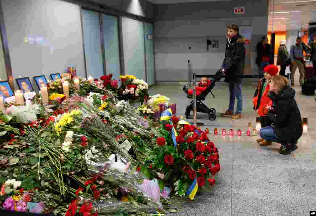 The collection of flowers and candles in front of portraits of the flight crew of the Ukrainian 737-800 plane that crashed on the outskirts of Tehran continues to grow at the Boryspil airport outside Kyiv, Ukraine, Jan.11, 2020.