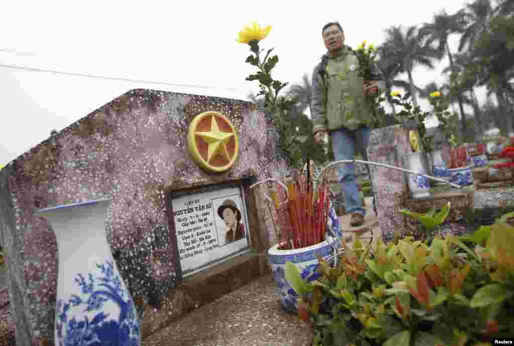 Anti-China protester Hoang Cong Cuong places flowers and incenses at the grave of Nguyen Van Su who died during the border war of China and Vietnam, at a military cemetery outside Hanoi February 16, 2014.