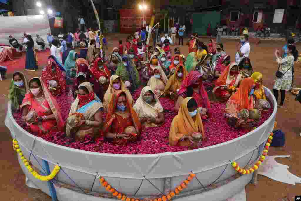 Indian women perform rituals standing inside an artificial pond on Chhat Puja festival in Mumbai, India.