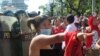 An unidentified female protester tore off her shirt at the demonstration Wednesday as riot police officers looked on. 