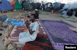 FILE - An African migrant prays near tents at a makeshift camp set up under the bridge of a motorway on the outskirts of Algiers, Algeria, June 28, 2017.