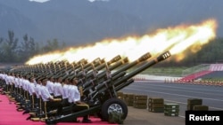 Paramilitary policemen and members of a gun salute team fire cannons during a training session for a military parade to mark the 70th anniversary of the end of the World War Two, at a military base in Beijing, China.