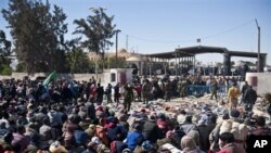 Refugees wait to cross the border in the Libyan side, near Ras Ajdir, Tunisia, Wednesday, March 2, 2011. (AP Photo/Benjamin Girette)