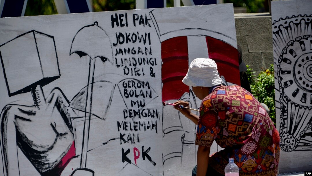 Seorang seniman melukis papan protes dalam unjuk rasa menentang revisi UU KPK di Banda Aceh, 17 September 2019. (Foto: AFP)