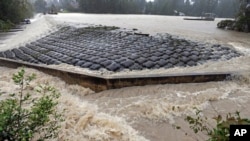 FILE - Floodwaters rush over a dam on Forest Lake in Columbia, South Carolina, Oct. 4, 2015.