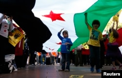 FILE - Children hold up a Syrian Opposition flag during a rally against the government of Syria and Egypt in central Sydney, Sept. 1, 2013.