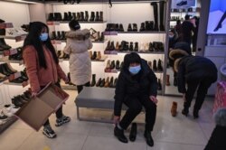 People wearing face masks to guard against COVID-19 visit a shoe shop in Wuhan, Hubei province, China, Jan. 22, 2021.