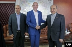 Iran's Minister of Sport and Youth Masoud Soltanifar, right, shakes hands with FIFA President Gianni Infantino during his visit to Tehran, March 1, 2018, accompanied by Iranian Football Federation President Mehdi Taj.