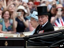FILE - Britain's Queen Elizabeth II and Prince Philip return to Buckingham Palace in a carriage, after attending the annual Trooping the Colour Ceremony in London, June 17, 2017.