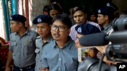 FILE - Reuters journalist Wa Lone, center, talks to journalists as he and Kyaw Soe Oo, back, leave the court after their trial in Yangon, Myanmar, May 21, 2018.