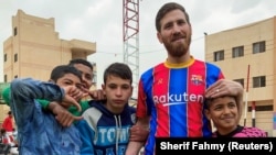 Islam Mohammed Ibrahim Battah, seorang berkebangsaan Mesir yang mirip dengan Lionel Messi, berpose dengan anak laki-laki, di kota Delta Nil Zagazig, utara Kairo, Mesir 23 Maret 2021. (Foto: REUTERS/Sherif Fahmy)