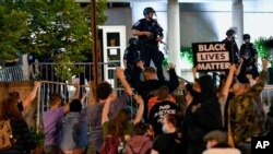 Protesters kneel in front of police officers outside the Public Safety Building in Rochester, N.Y., Sept. 3, 2020. 