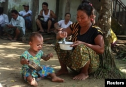 FILE - An ethnic Rakhine woman who fled from recent violence in Maungdaw feeds her daughter at a monastery used as a temporary internally displaced persons (IDP) camp in Sittwe, Myanmar, Oct. 15, 2016.