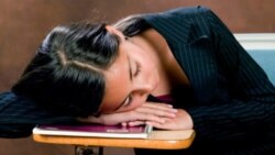 A teenager sleeps at a school desk