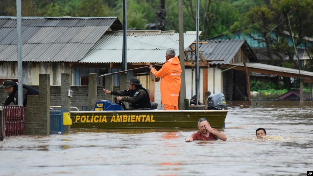 Agentes de policía revisan una casa mientras habitantes vadean una calle inundada por tormentas derivadas de un ciclón en Passo Fundo, en el estado de Rio Grande do Sul, Brasil, el 4 de septiembre de 2023.