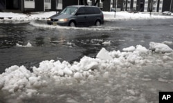 A van drives through a flooded street as ice and snow prevent drainage, Jan. 23, 2016, in Atlantic City, N.J.
