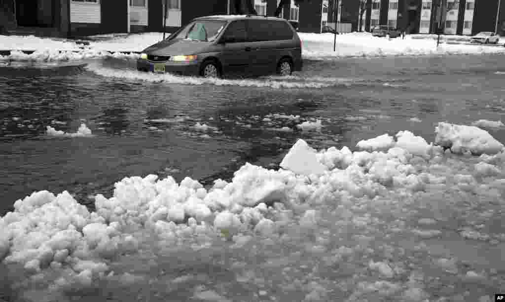 A van drives through a flooded street as ice and snow prevent drainage, Jan. 23, 2016, in Atlantic City, N.J. (AP Photo/Mel Evans)