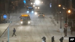 Pejalan kaki melewati jalan-jalan licin di Chicago, Kamis, 22 Desember 2022. Badai musim dingin yang dahsyat akan melanda sebagian besar wilayah AS selama beberapa hari mendatang. (AP/Charles Rex Arbogast)