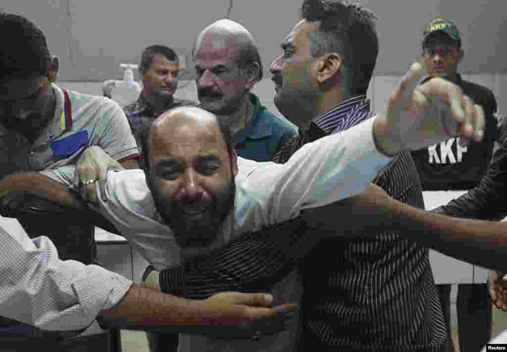 A relative mourning the death of Waqas Ali Shah, a supporter of the Muttahida Qaumi Movement (MQM) political party who was killed during a raid by paramilitary forces on MQM&#39;s headquarters, is comforted by others at a hospital morgue, in Karachi, March 11, 2015.