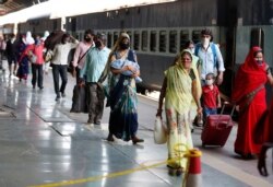 Migrant laborers from Gujarat state walk at a railway station after arriving in their home state in Prayagraj, India, May 6, 2020.