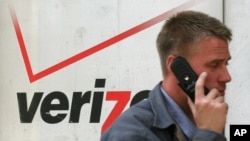 A cell phone user passes a Verizon store in New York in this April 27, 2006 file photo.