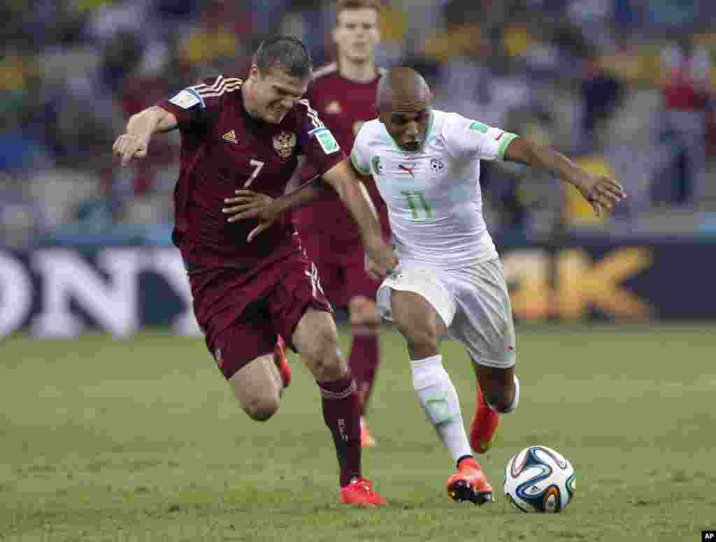 Yacine Brahimi de l'Algérie, à droite, et Igor Denisov de la Russie se battent pour le ballon lors du match de la Coupe du monde du groupe H entre l'Algérie et la Russie à l'Arena da Baixada à Curitiba, au Brésil, jeudi 26 Juin 2014.