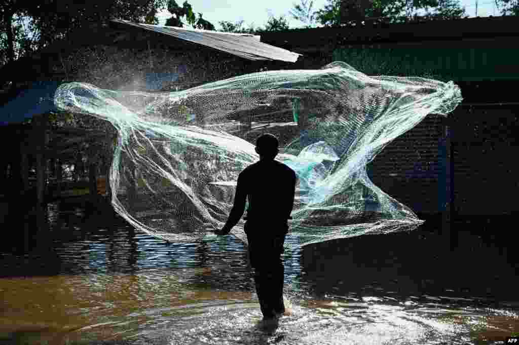 A resident goes fishing in his partially submerged village in the central Thai province of Lopburi, Sept. 28, 2021, as tropical storm Dianmu caused flooding in 30 provinces across the country.