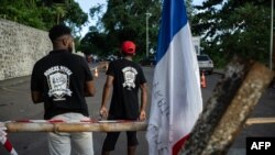 FILE - Members of the Forces Vives collective stand during a roadblock set up by residents of surrounding villages to protest against living conditions and insecurity on the island of Mayotte, on February 13, 2024.