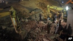 Pakistan rescue workers use heavy machinery to remove debris of a collapsed building in Lahore, Pakistan, Wednesday, Nov. 4, 2015.