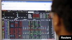 FILE - An investor looks at a stock market screen at a securities company in Hanoi, Vietnam, July 20, 2015. 