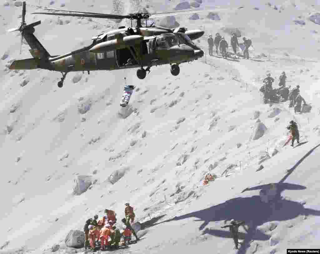 Seorang pejalan kaki diangkat dengan helikopter penyelamat dari Pasukan Bela Diri Jepang&nbsp;&nbsp;(JSDF ), dalam operasi penyelamatan di gunung Ontake, yang terbentang di antara wilayah Nagano dan Gifu, Jepang tengah (28/9). 