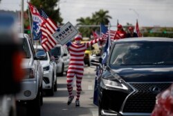 2020年11月1日迈阿密特朗普总统支持者穿国旗主题长袜走在两排汽车之间。