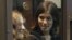 Band members Maria Alyokhina, left, and Nadezhda Tolokonnikova in a glass-walled cage before a Russian court hearing, Moscow, October 10, 2012.