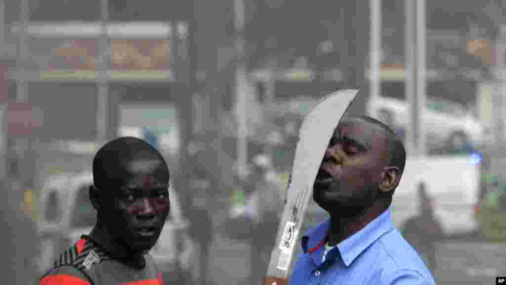 Un immigrant armé d&#39;une machette, aperçu sur une rue au cours d&#39;affrontements avec la police et des xénophobes qui ont attaqué les propriétaires de magasins étrangers dans le centre-ville à Durban, Afrique du Sud, mardi 14 Avril 2015.