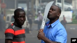 Un immigrant armé d'une machette, aperçu sur une rue au cours d'affrontements avec la police et des xénophobes qui ont attaqué les propriétaires de magasins étrangers dans le centre-ville à Durban, Afrique du Sud, mardi 14 Avril 2015. 