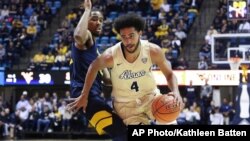 In this Nov. 8, 2019, file photo, Akron's Tyler Cheese is defended by West Virginia's Taz Sherman during an NCAA college basketball game in Morgantown, W.Va. 