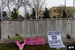 Flowers and signs are left in front of the security fence at the start of curfew to protest the death of Daunte Wright who was shot and killed by a police officer in Brooklyn Center, Minnesota on April 12, 2021.